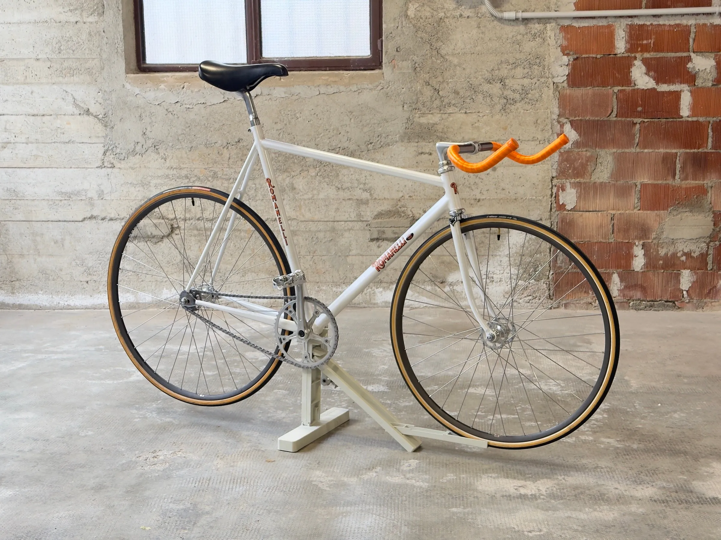 Bicicletta da pista Pursuit in acciaio bianco con manubrio arancione, vista laterale — Romanelli Cicli Nose’ n’ toes Pursuit